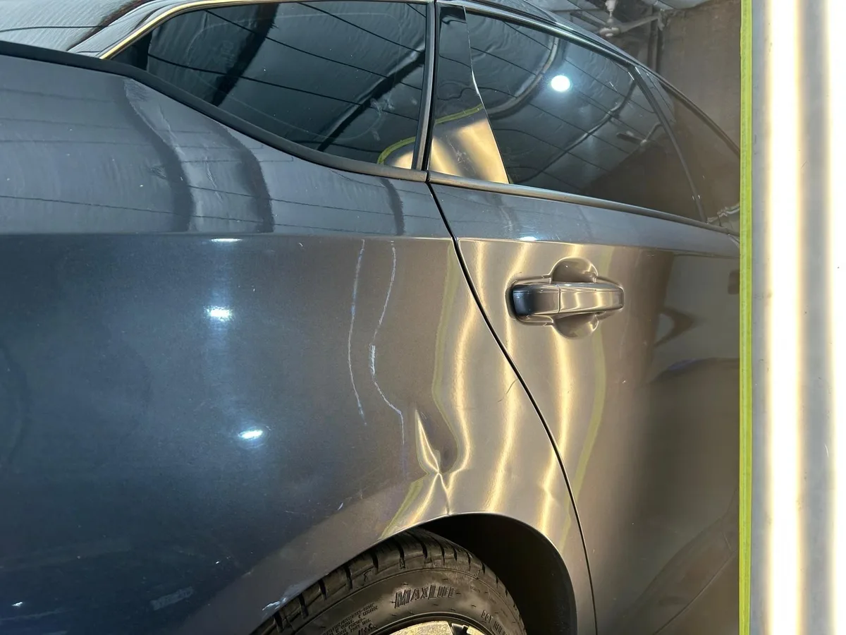 Hail dent visible on a vehicle door panel before repair